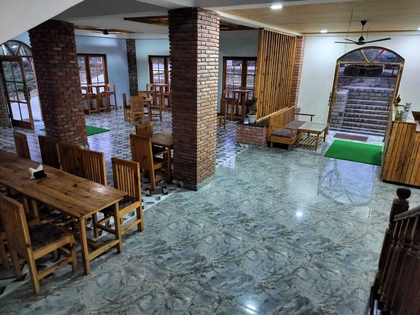 Amplio espacio interior con mesas y sillas de madera, pilares de ladrillo y piso de mármol.
