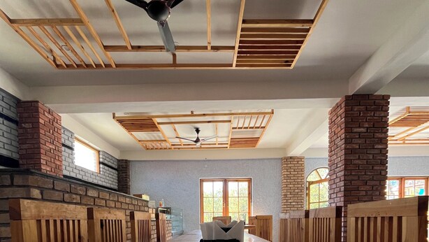 A spacious room with a long wooden table, brick walls, and a ceiling fan.
