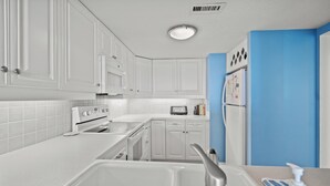 A modern kitchen with white cabinets, a built-in oven, a microwave, and a refrigerator. - Oceanfront 3-bedroom Condo - North Myrtle Beach (Myrtle Beach)
