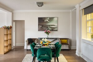 A dining area with a table set for four, a sofa, and a bookshelf. - 4-bdr Stunning Kensington Penthouse (London)