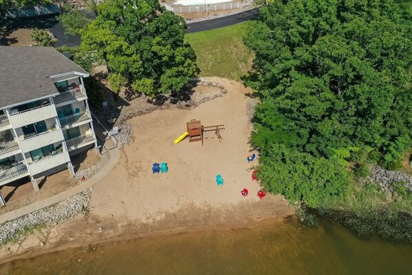 Un área de playa con mesa de billar, varias sillas de playa y un edificio con múltiples balcones.