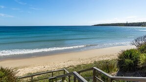 A beach with a wooden walkway leading to the shore.
