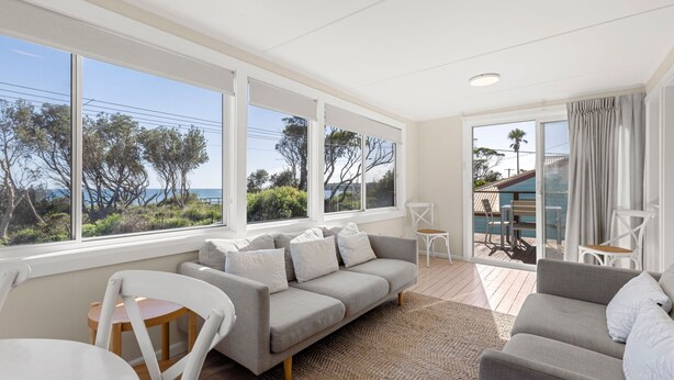 A spacious living area with a large window overlooking a scenic view, a cozy seating arrangement, and a wooden deck area.