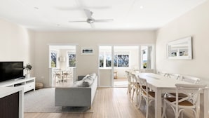 A modern living room with a sofa, TV, and dining area with chairs and a table.