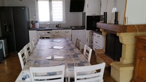 Eine moderne Küche mit Esstisch und Stühlen, einem schwarzen Kühlschrank, einem Herd und einem an der Wand montierten Fernseher.
