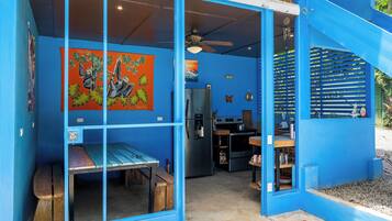 A blue building with a kitchen area, a dining table, and a bench.