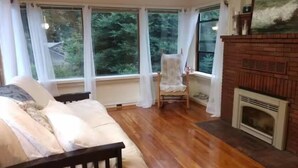 Un salon chaleureux avec un plancher en bois, un canapé, un fauteuil et une cheminée.
