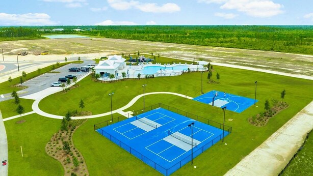 Ein Sportkomplex mit mehreren Tennisplätzen, einem Schwimmbad und einem Gebäude mit weißer Fassade.