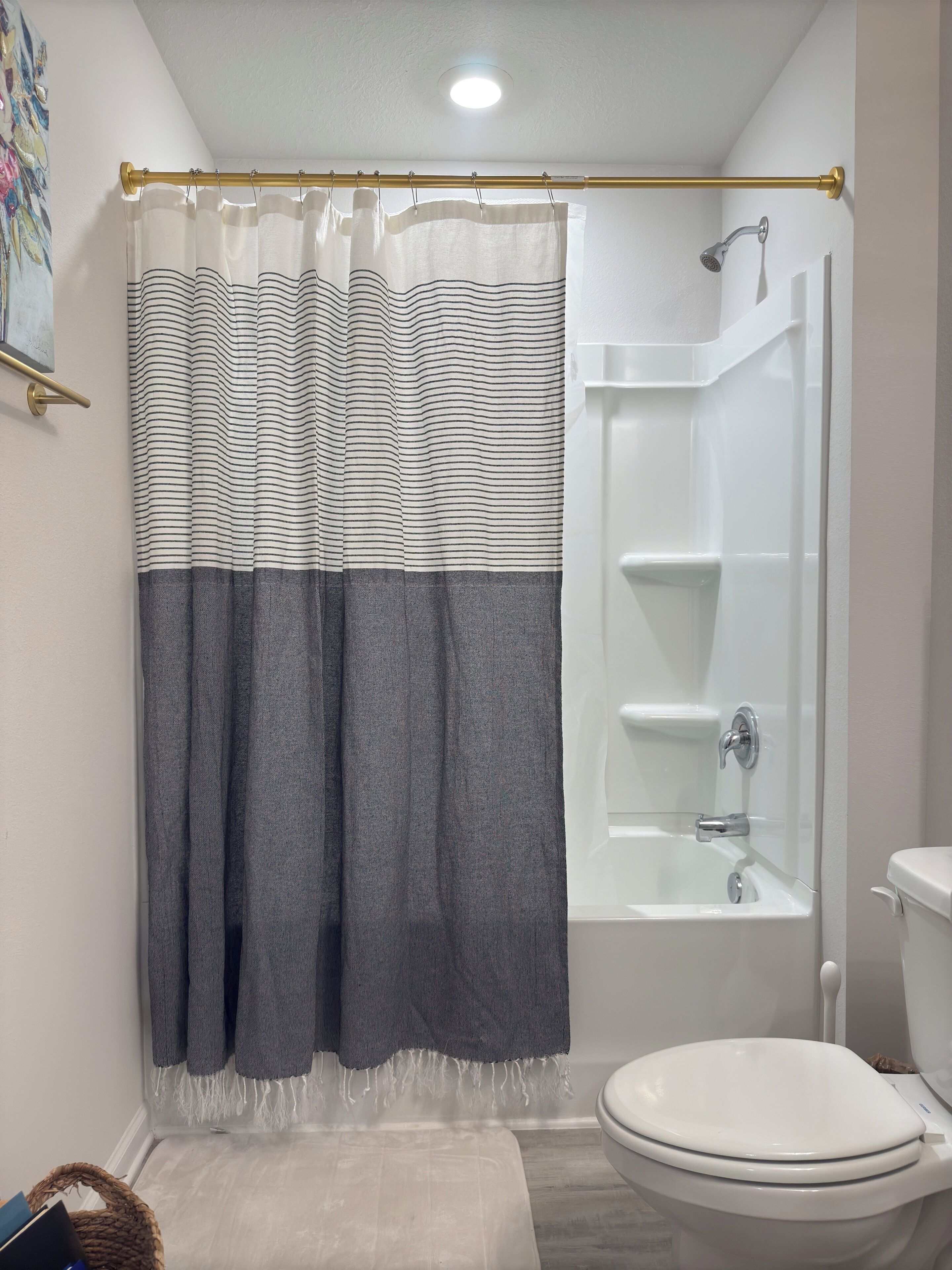 A bathroom with a shower, toilet, and a towel rack.