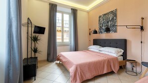 A bedroom with a bed, a TV, a painting, and a plant. - Whiteten Rome Apartment (Roma)