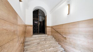 A marble staircase with a black gate at the top, leading to a doorway. - Whiteten Rome Apartment (Roma)