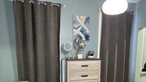 Une chambre à coucher avec un lit, une commode, une chaise, un miroir et un tableau accroché au mur.