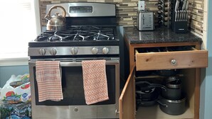 Une cuisine compacte dotée d’une cuisinière en acier inoxydable, de meubles en bois et d’un dosseret carrelé.