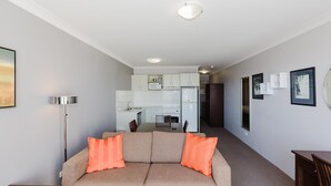 A modern apartment with a living room, kitchenette, and a hallway leading to a bedroom. - Horizons - 418/10 Kosciuszko Road (Jindabyne)