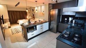 A modern kitchen with a central island, built-in appliances, and pendant lighting. - Studio Shopping OKA Floripa - Campeche - SOK125 (Florianópolis)