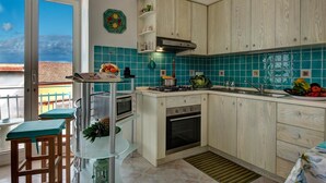 Une cuisine avec vue sur la ville, un balcon avec une table et des chaises, et divers appareils de cuisine.