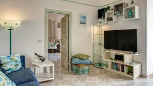 Un salon avec un canapé, une table basse, un téléviseur et une bibliothèque.