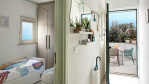 Une chambre à coucher comprenant un lit, une armoire, une fenêtre, une salle de bain avec un miroir, et un balcon avec une table et des chaises.