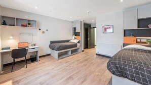 A modern bedroom with a bed, a desk, and a chair. There is a whiteboard on the wall and a shelf with decorative items. - The Residence Dublin (Dublin)