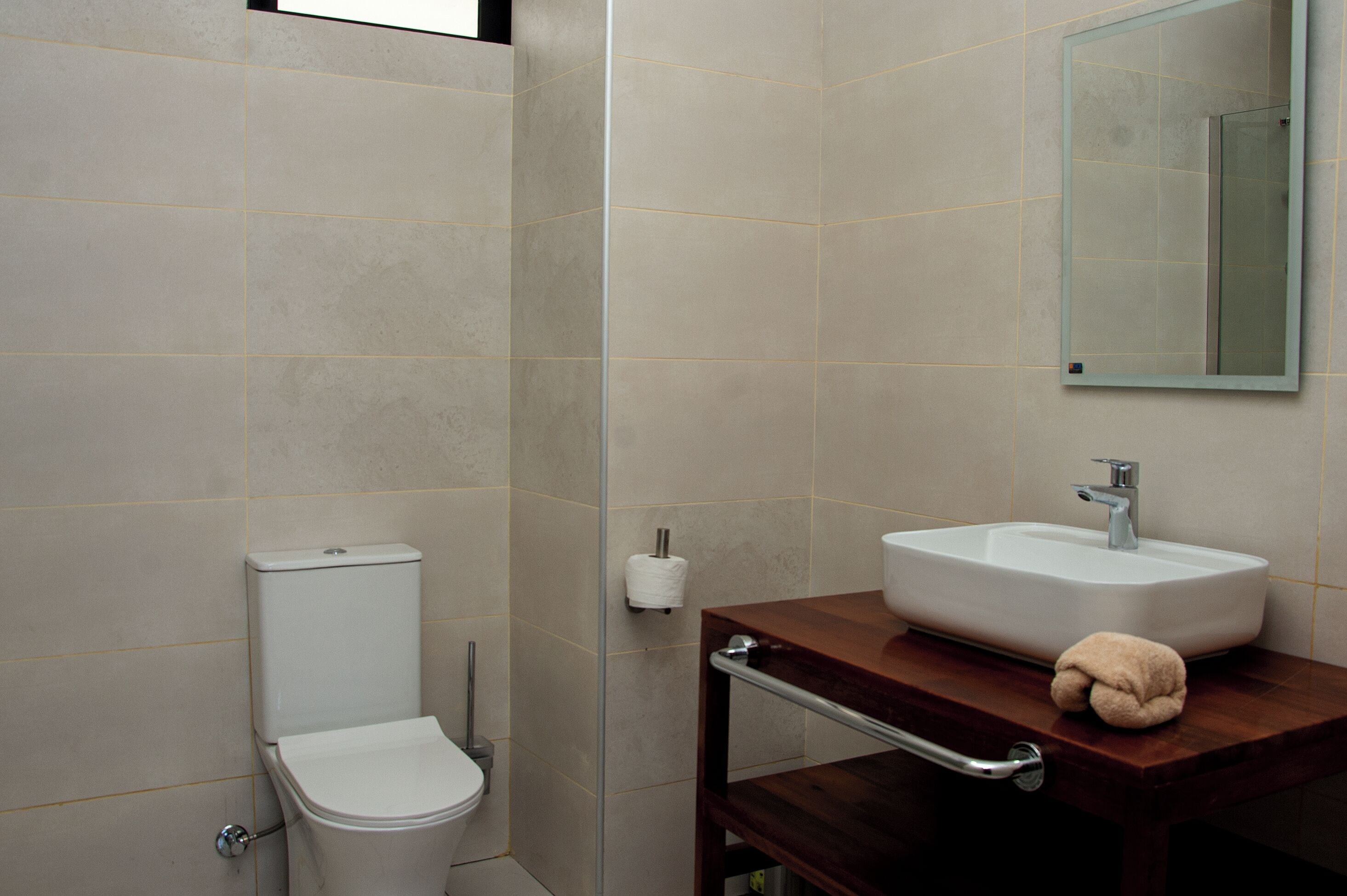 Egy fürdőszoba, amelyben WC, mosdókagyló és tükör található.