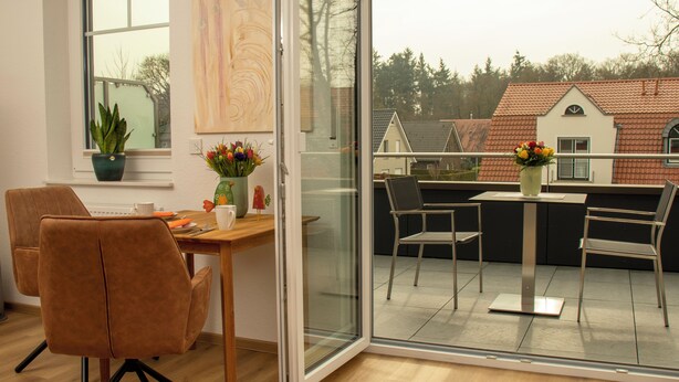 A modern interior with a dining area, a potted plant, and a view of the outside.