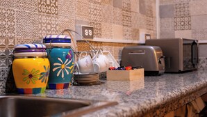 Une cuisine avec des carreaux décoratifs, un grille-pain et des bocaux colorés sur le plan de travail.