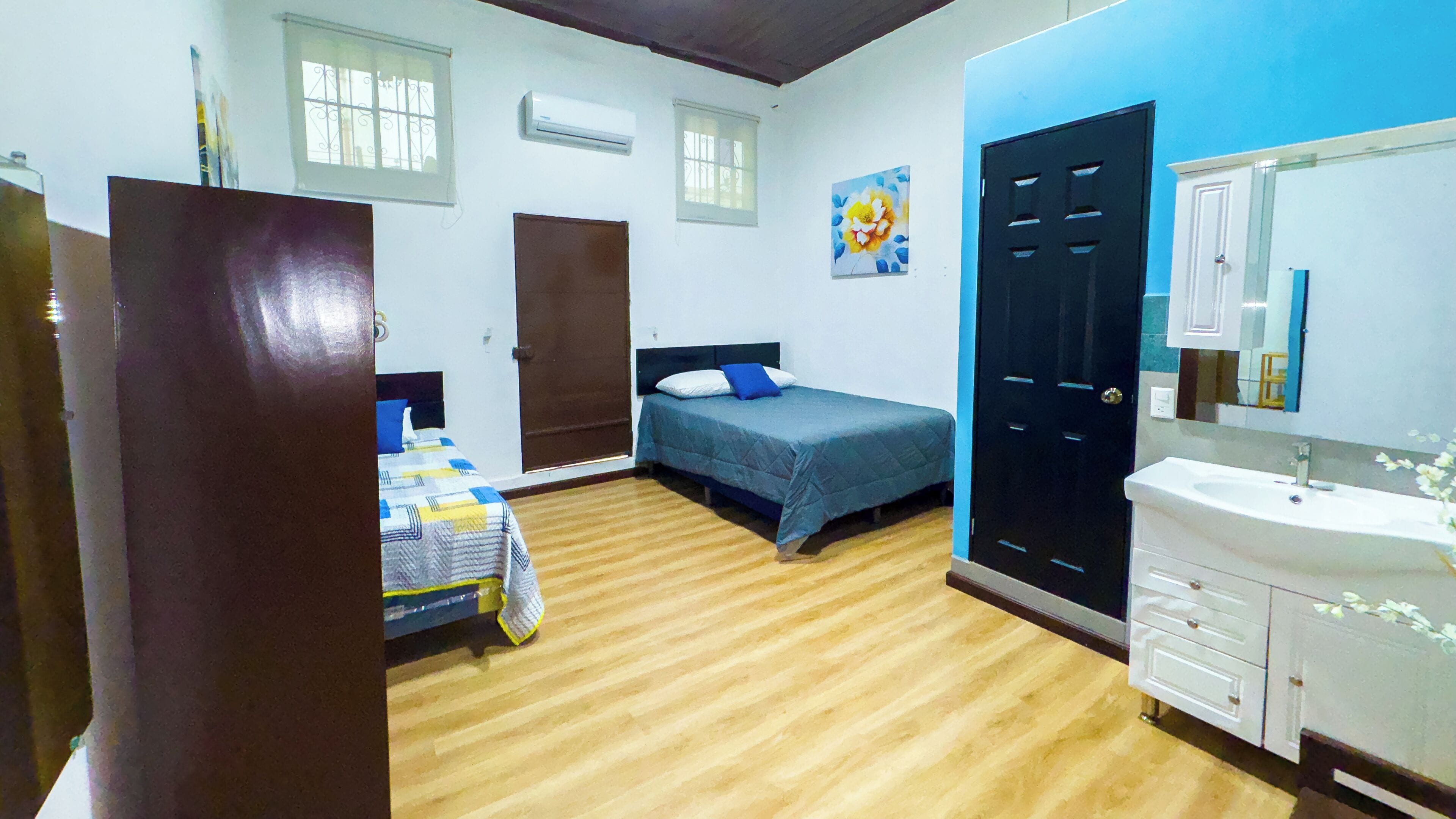 Quarto com duas camas, banheiro com pia e porta.