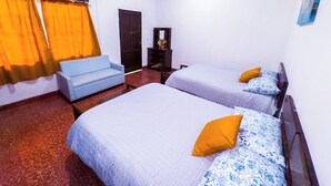Une chambre d’hôtel avec deux lits, un canapé, une commode et un miroir.