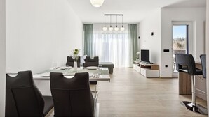 Un espace repas moderne avec une table dressée pour deux personnes, un téléviseur et un coin bar avec des sièges.