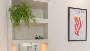 Et moderne hotelværelse med et træskrivebord, en potteplante og et indrammet kunstværk på væggen.