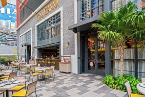 Een terras met tafels en stoelen, een bar, en een gebouw met een bordje waarop 