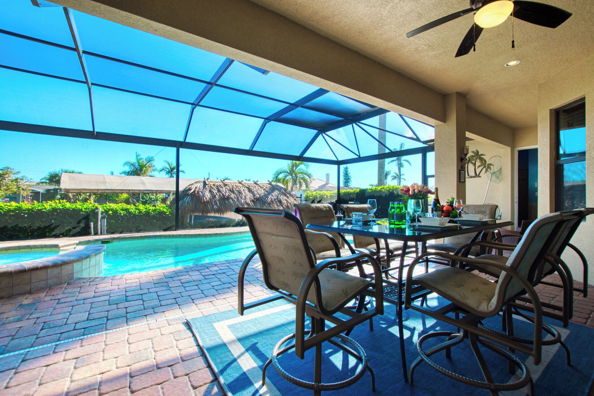 Ein Poolbereich mit einer verglasten Terrasse, Sitzgelegenheiten im Freien und Blick auf einen Pool sowie eine tropische Landschaft.