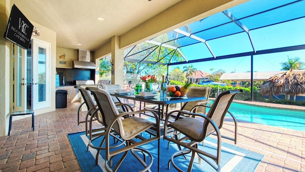 A patio with a glass enclosure, a pool, and outdoor furniture. - VRCC Villa Poseidon’s Paradise (Cape Coral)