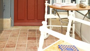 Une porte rouge, une chaise blanche et une petite table avec un livre.