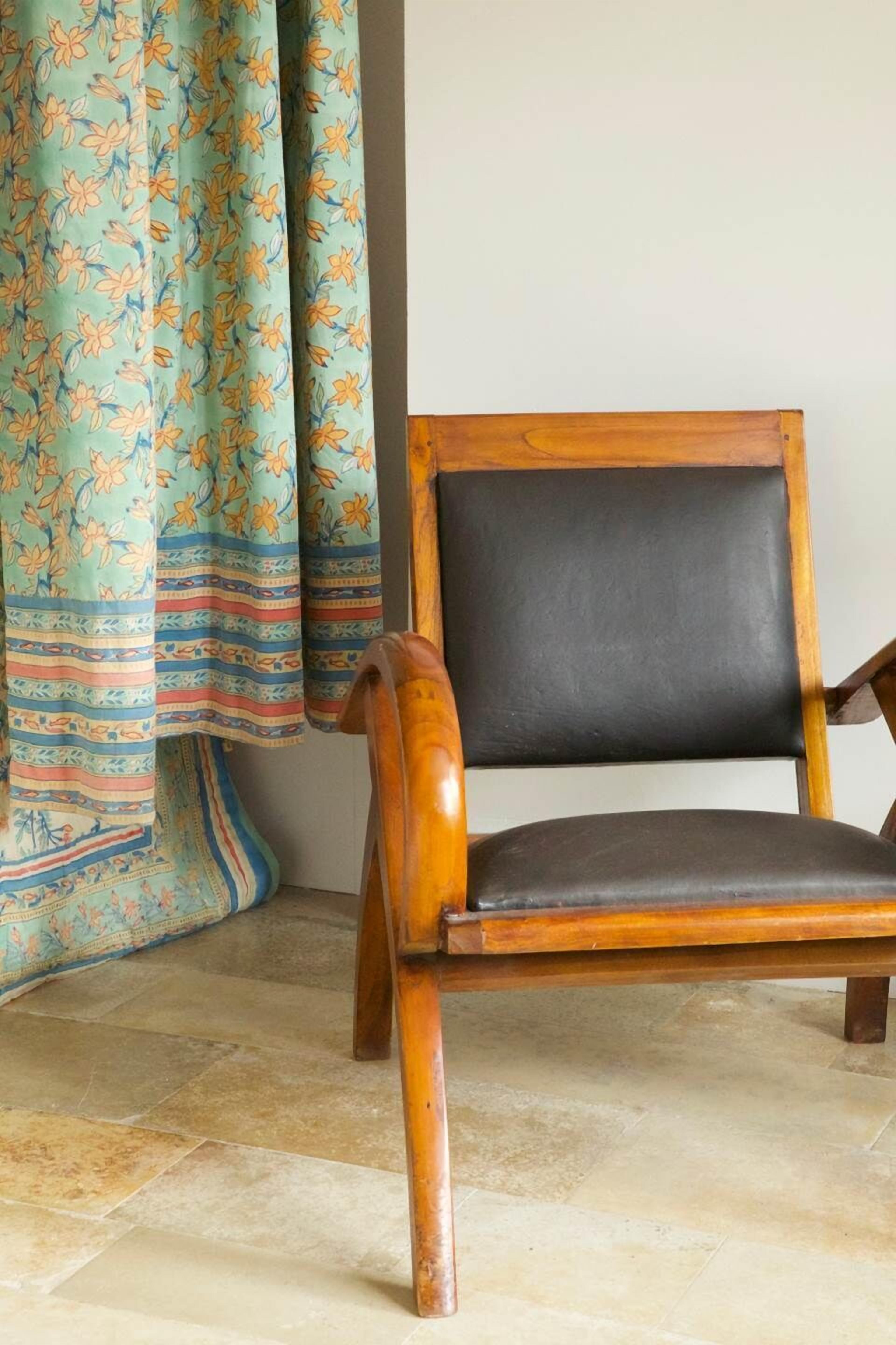 Una silla de madera con asiento y respaldo negros, sobre un piso de baldosas.
