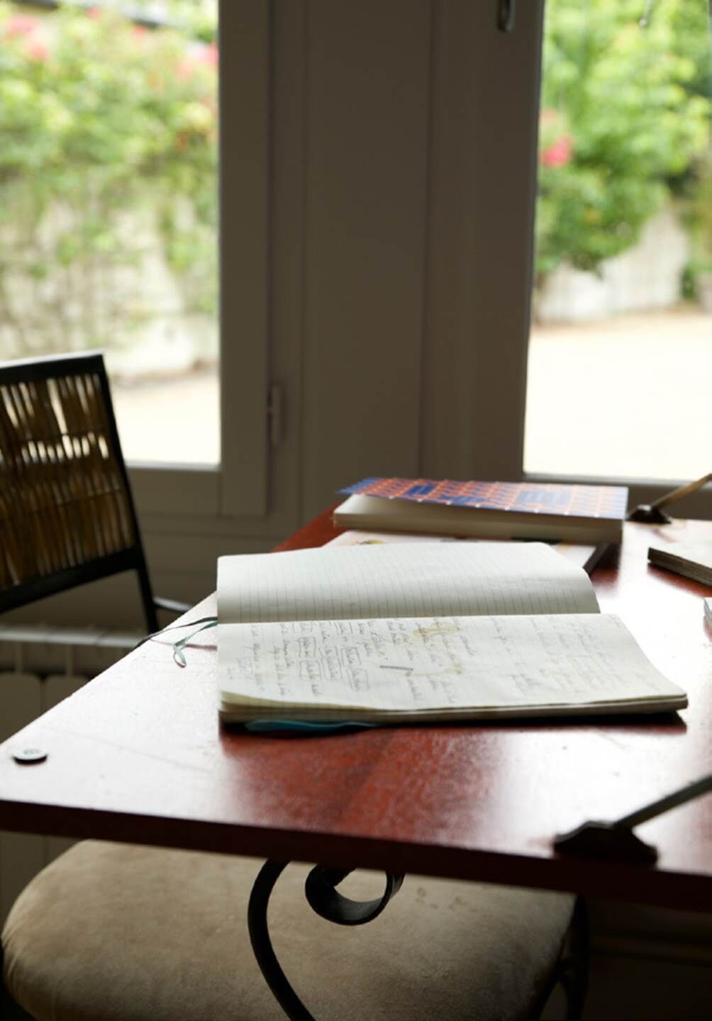A desk with an open notebook, a closed book, and a pen.