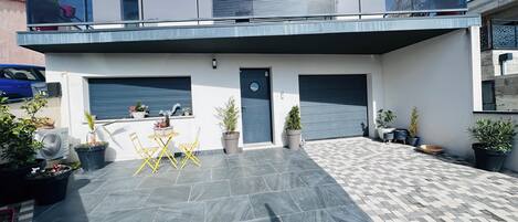 Una casa moderna de dos pisos con balcón, patio cubierto y garaje.