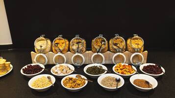 A variety of food items displayed in bowls and jars, likely in a buffet setting.