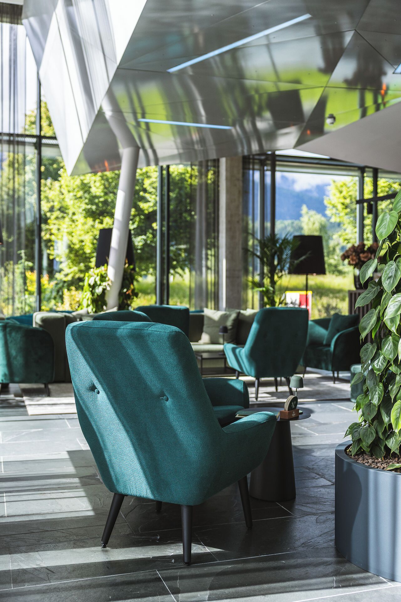 Un área de estar al aire libre moderna con sillas color turquesa y una planta en maceta.