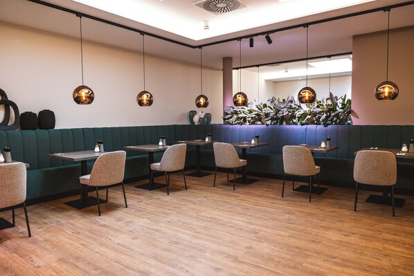 A restaurant interior with booths, tables, and hanging pendant lights. - DION Hotel Wattens (Wattens)