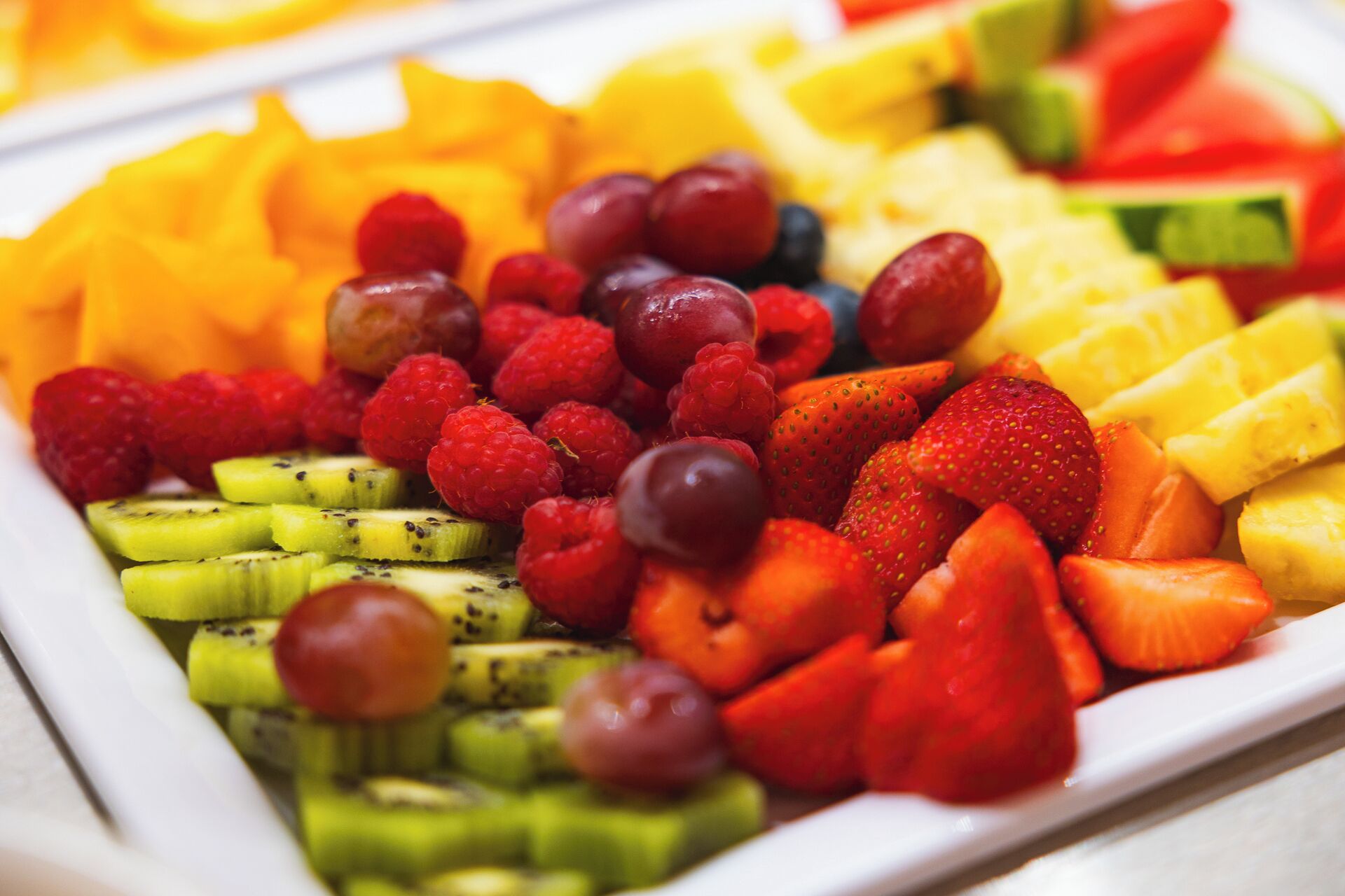 Eine Auswahl frischer Früchte, darunter Erdbeeren, Himbeeren und Kiwi-Scheiben.