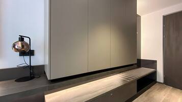 Une chambre moderne et minimaliste, dotée d’une banquette intégrée, d’une lampe fixée au mur et d’une grande armoire.