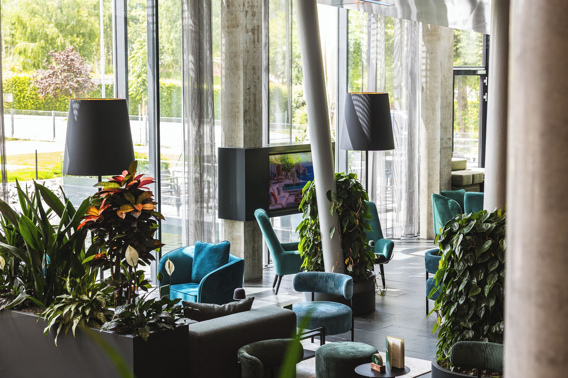 Un área de estar moderna con asientos, ventanas amplias y plantas de interior.