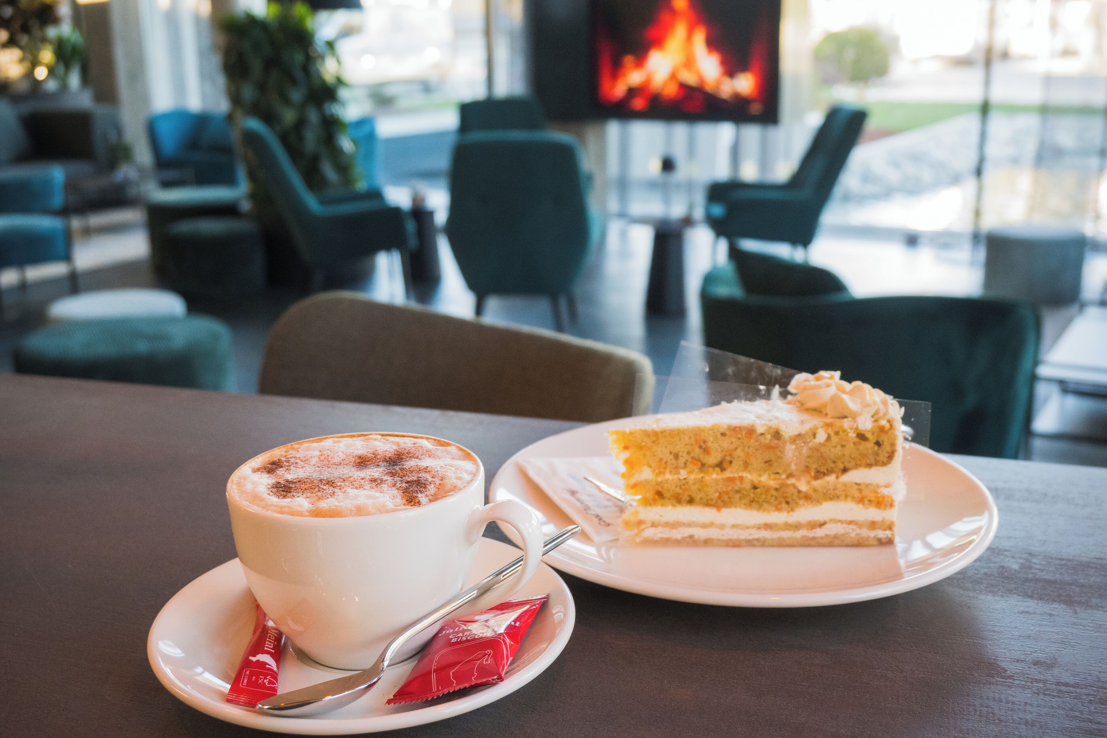 A dining area with a table, a cup of coffee, and a slice of cake.