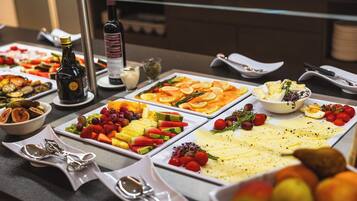 Un bufé con diversas opciones de comida, como frutas, quesos y ensaladas.