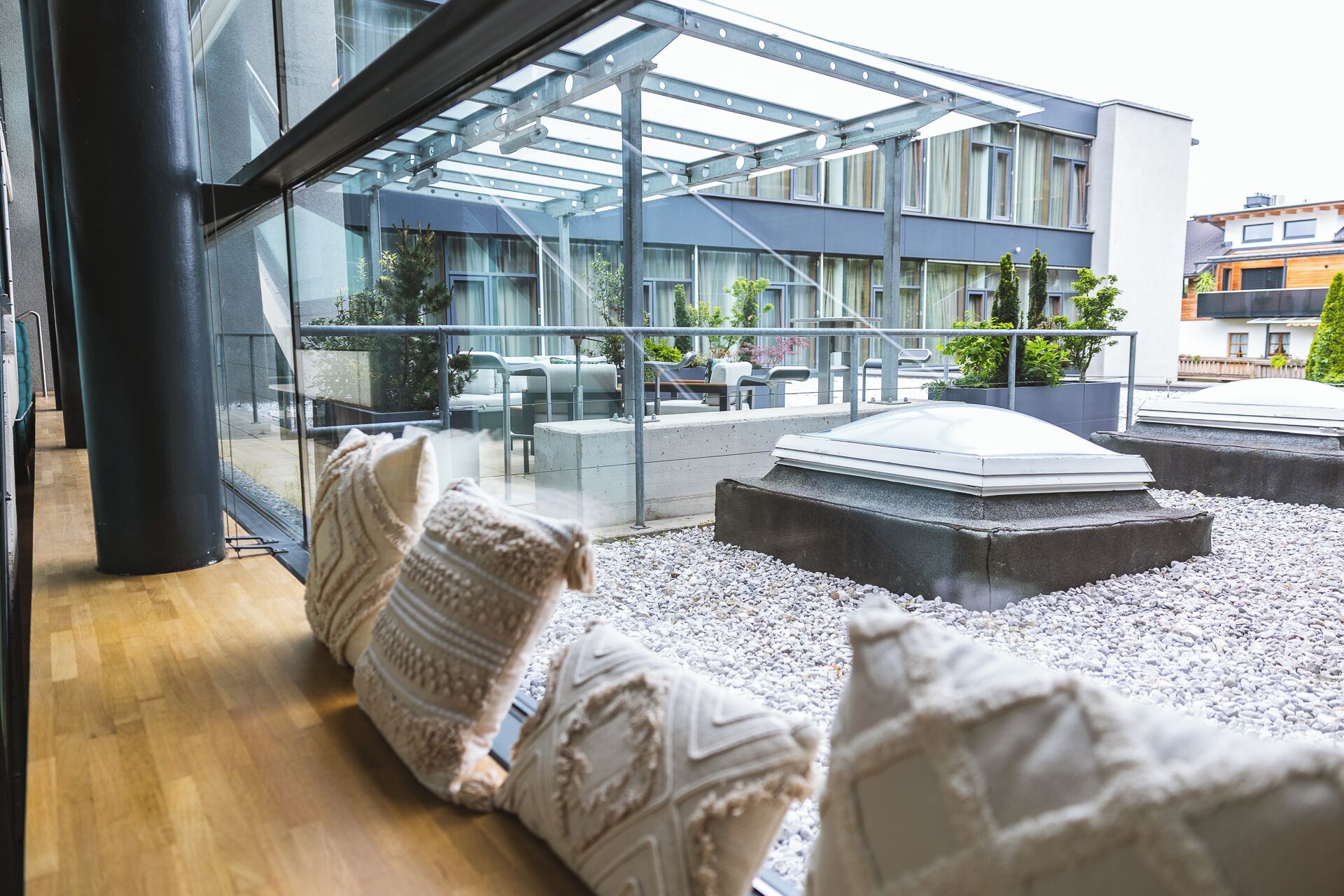 Ein moderner Außenbereich mit Glasveranda, Steinofen und Blick auf ein Gebäude mit vielen Fenstern.