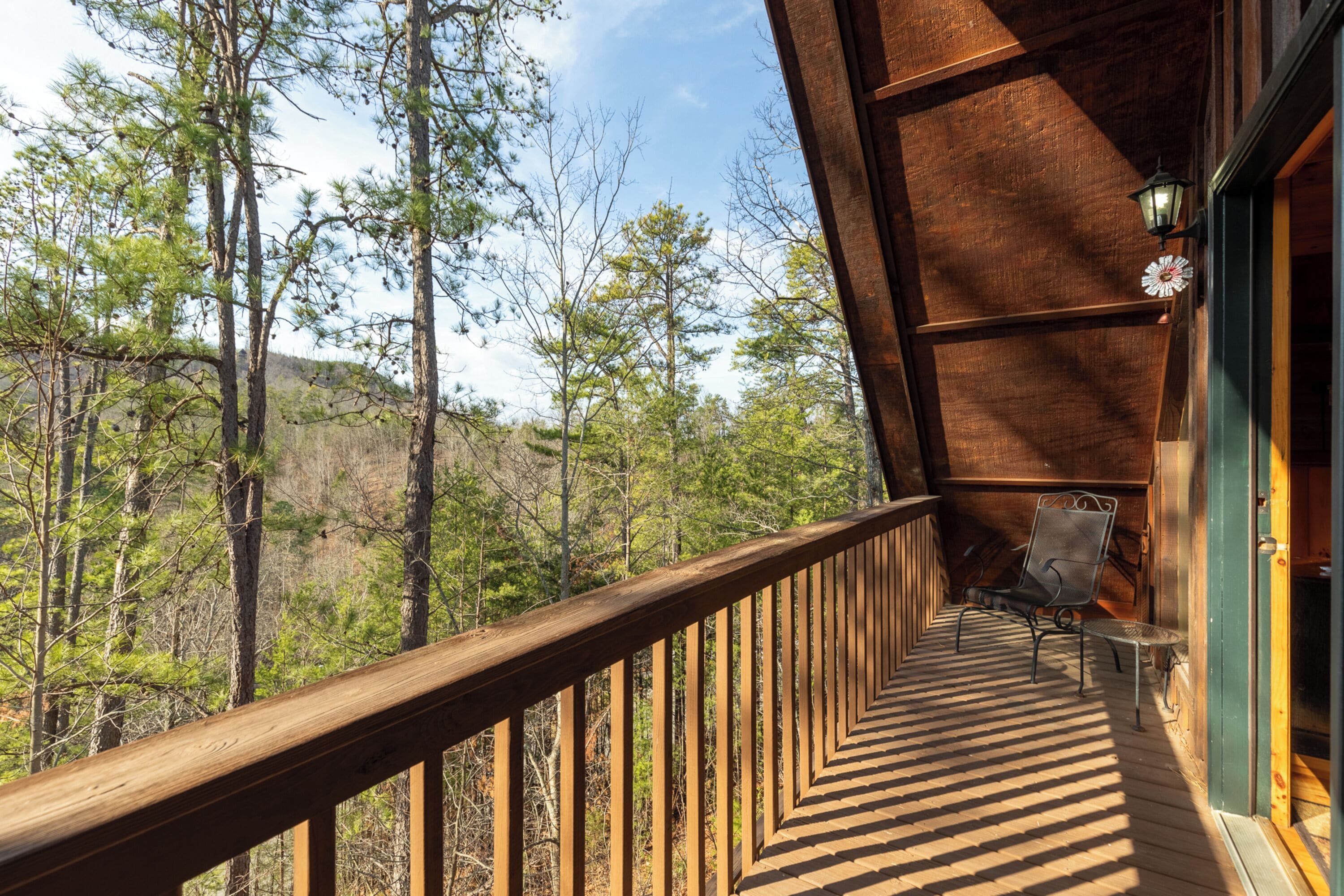 A wooden deck with a railing overlooking a forested area.