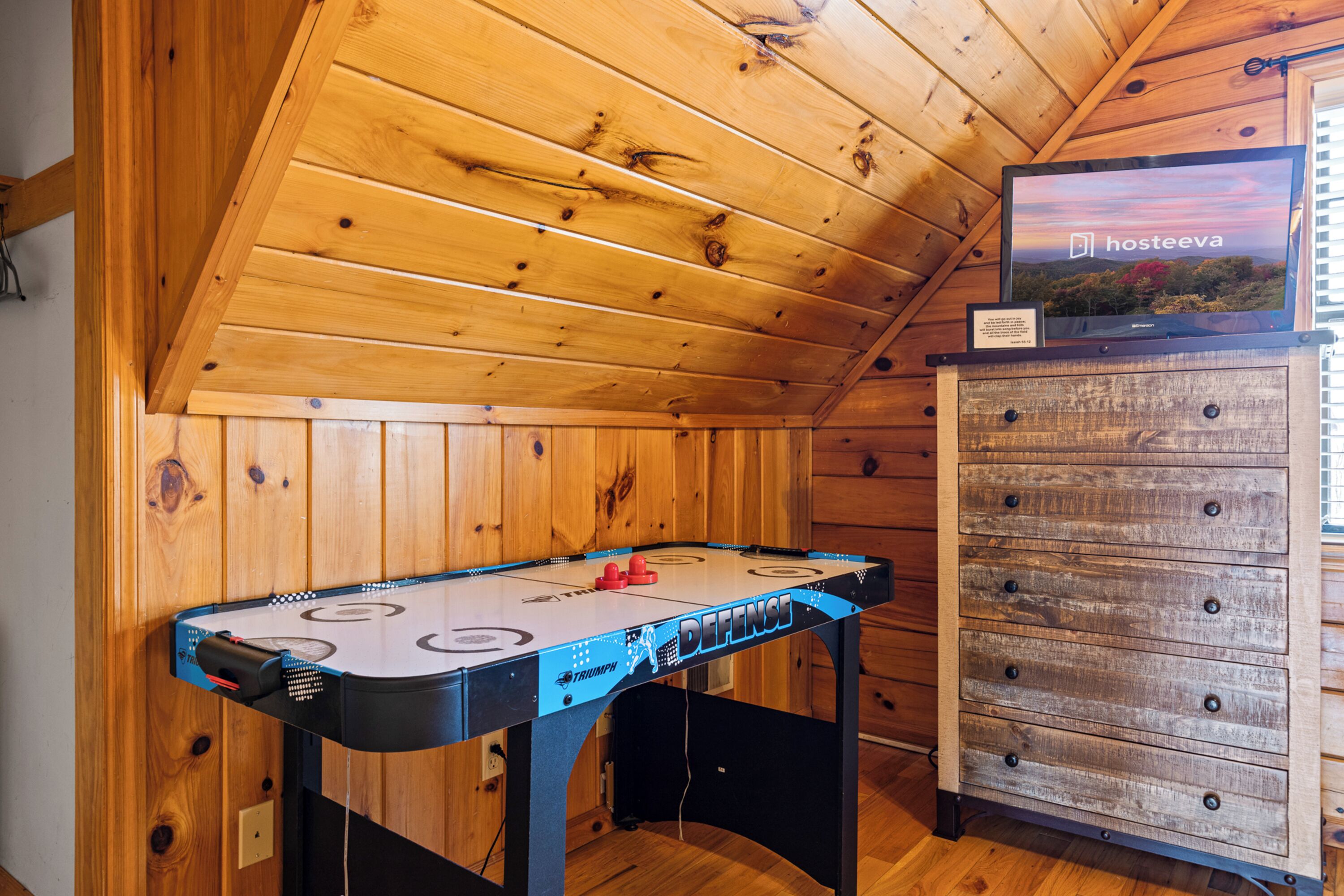 A wooden room with a foosball table and a TV on a wooden cabinet.