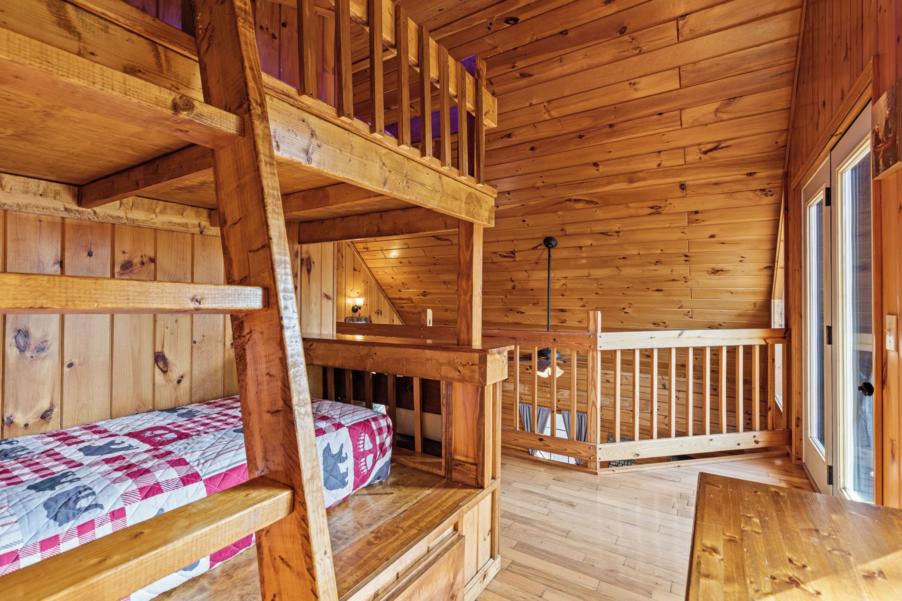 Una cabaña de madera con literas, un balcón y una terraza de madera.