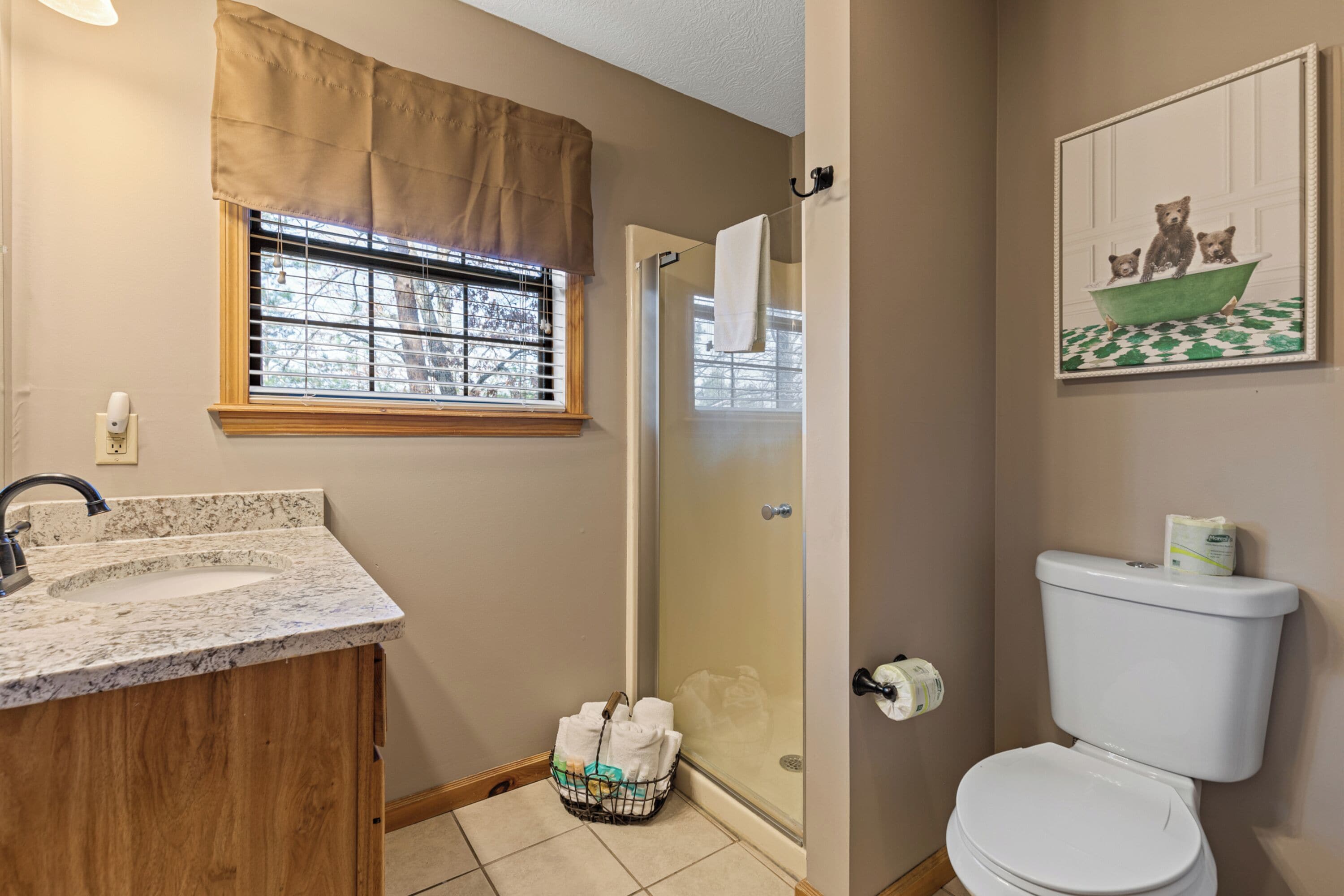 A bathroom with a marble sink, a glass shower enclosure, and a toilet.
